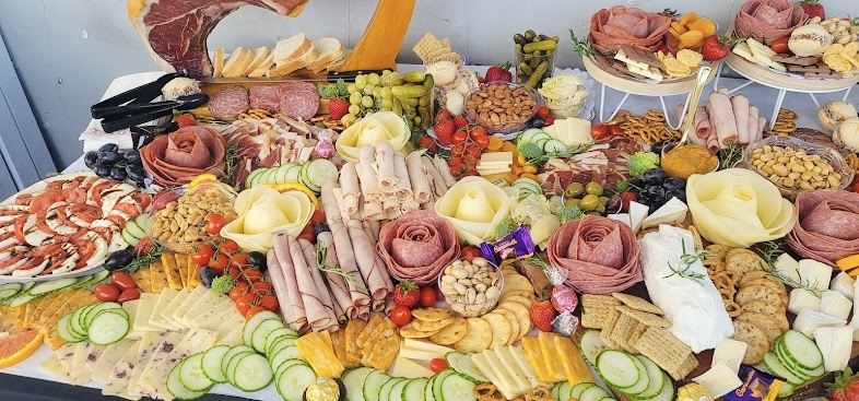 A large charcuterie spread with salami roses, cheeses, fruit and crackers